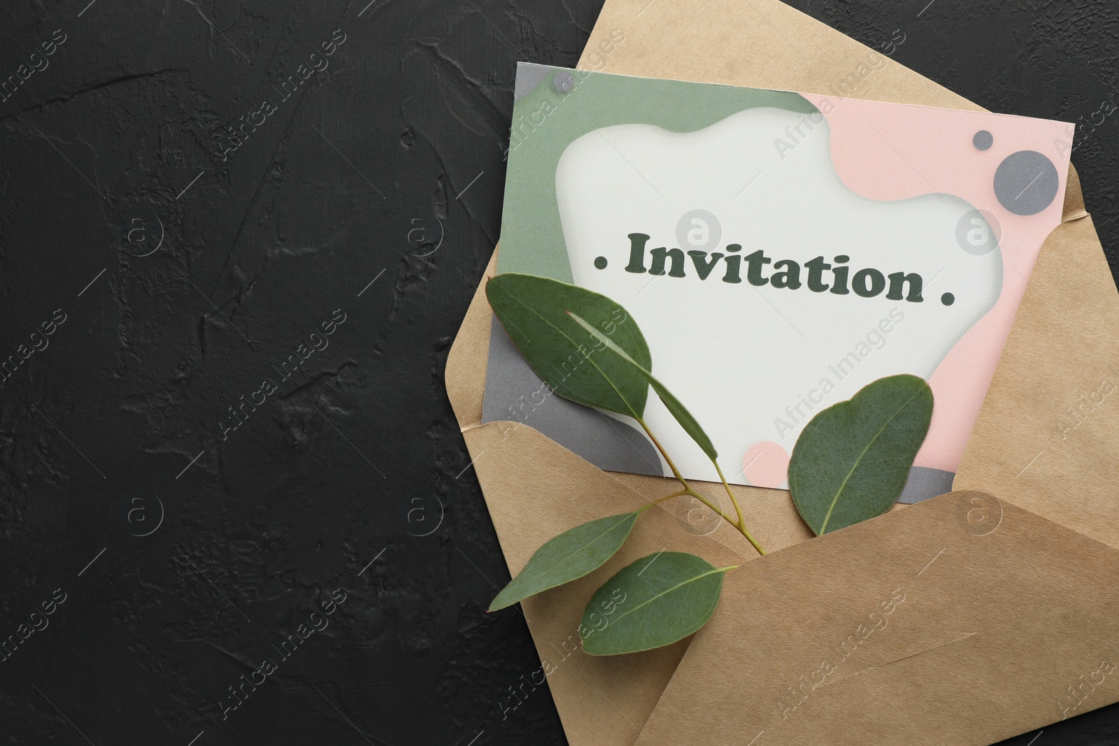 Photo of Card with word Invitation, envelope and green leaves on black textured background, top view. Space for text