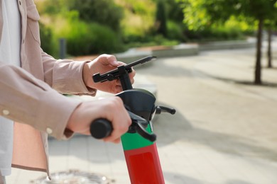 Photo of Man using smartphone to pay and unblock electric kick scooter outdoors, closeup. Space for text
