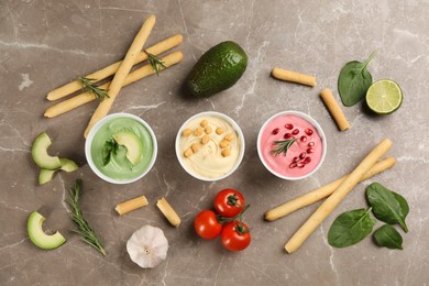 Photo of Flat lay composition with different delicious hummuses on brown marble table