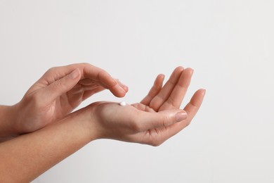 Photo of Woman applying cosmetic cream onto hand on white background, closeup