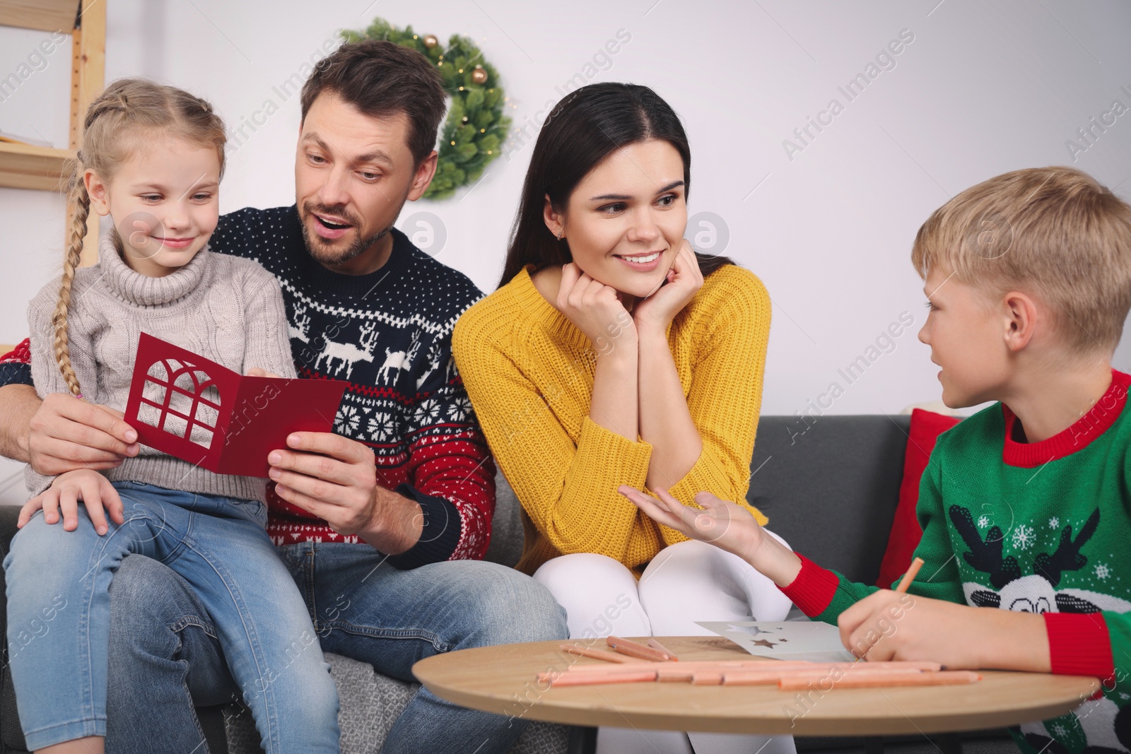 Photo of Cute children with their parents making beautiful Christmas greeting cards at home