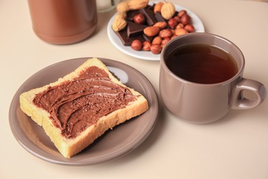 Photo of Tasty toast with chocolate paste and cup of tea served on light table