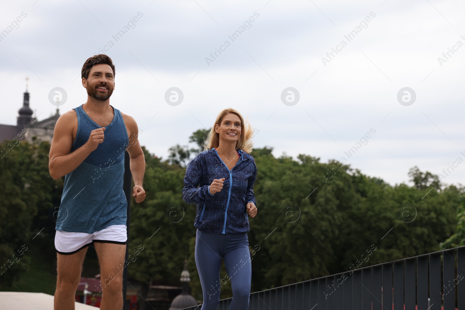 Photo of Healthy lifestyle. Happy sporty couple running outdoors, space for text