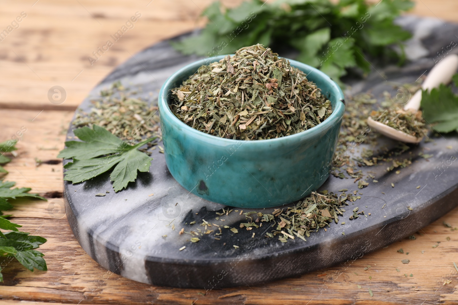 Photo of Dried parsley in bowl on wooden table, closeup