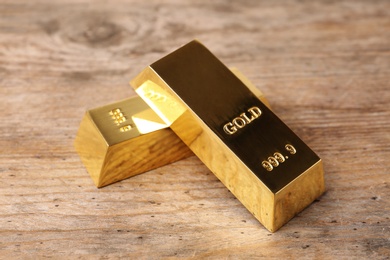 Photo of Precious shiny gold bars on wooden background