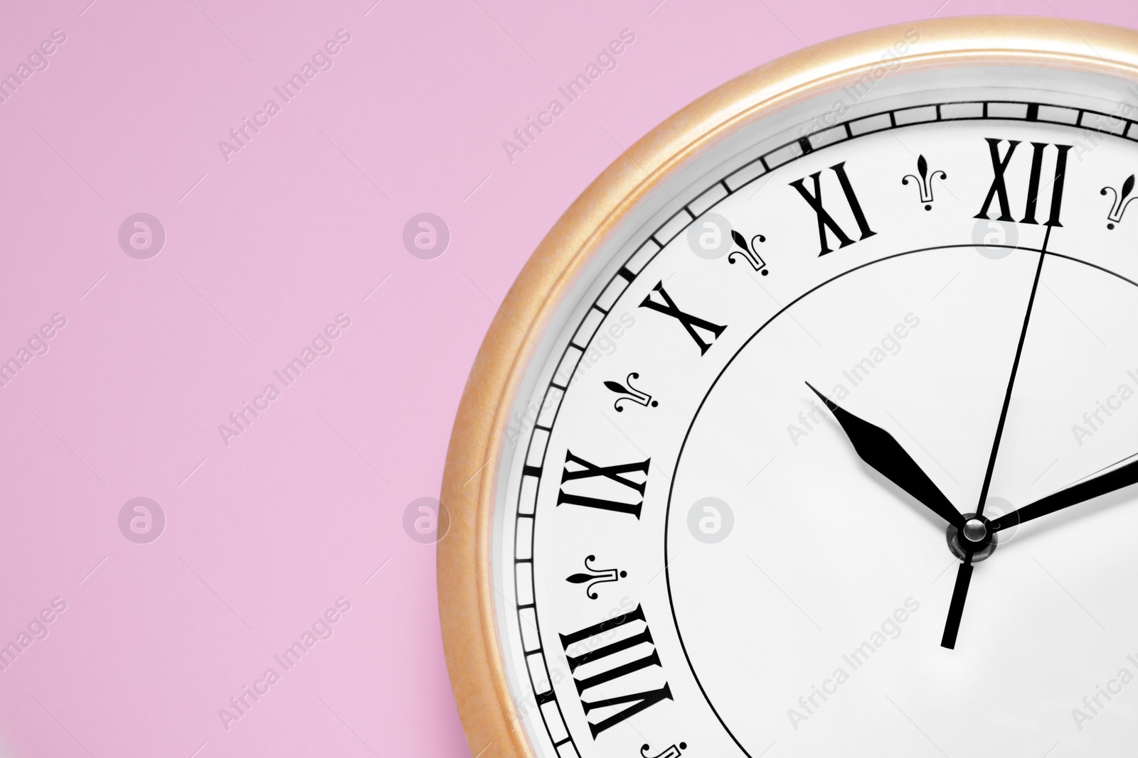 Photo of Stylish round clock on pale pink background, top view with space for text. Interior element