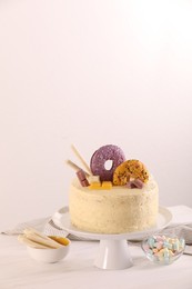 Photo of Delicious cake decorated with sweets, wafer rolls and marshmallows on white wooden table, space for text