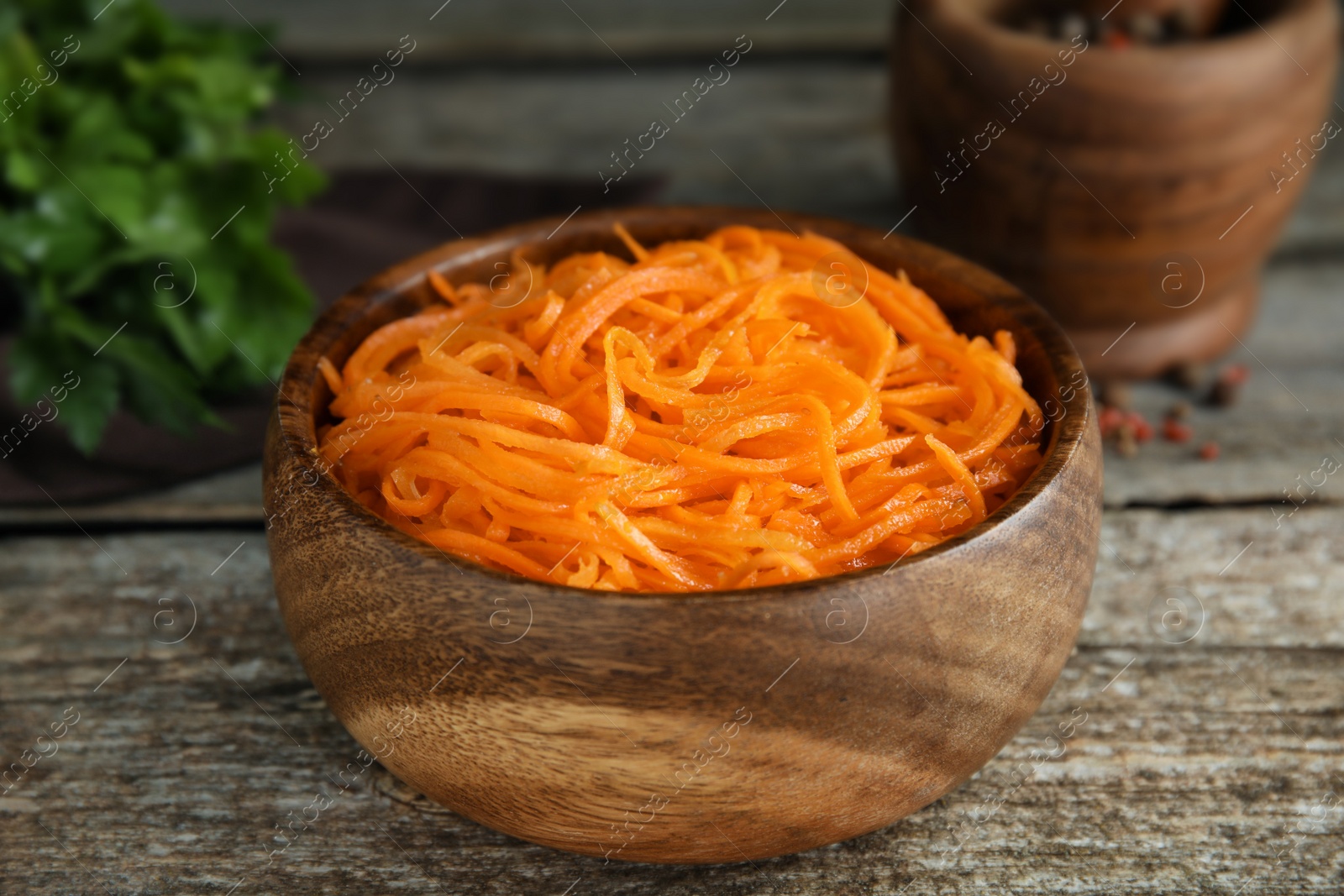 Photo of Delicious Korean carrot salad in bowl on wooden table