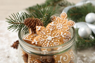 Photo of Tasty Christmas cookies in glass jar and festive decor on table, closeup