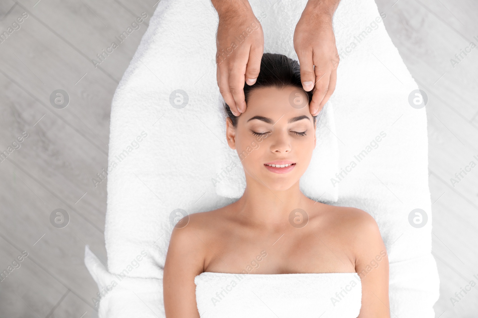 Photo of Relaxed woman receiving head massage in wellness center, top view