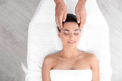 Photo of Relaxed woman receiving head massage in wellness center, top view