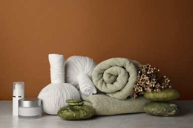 Photo of Composition with different spa products and flowers on beige table against brown background