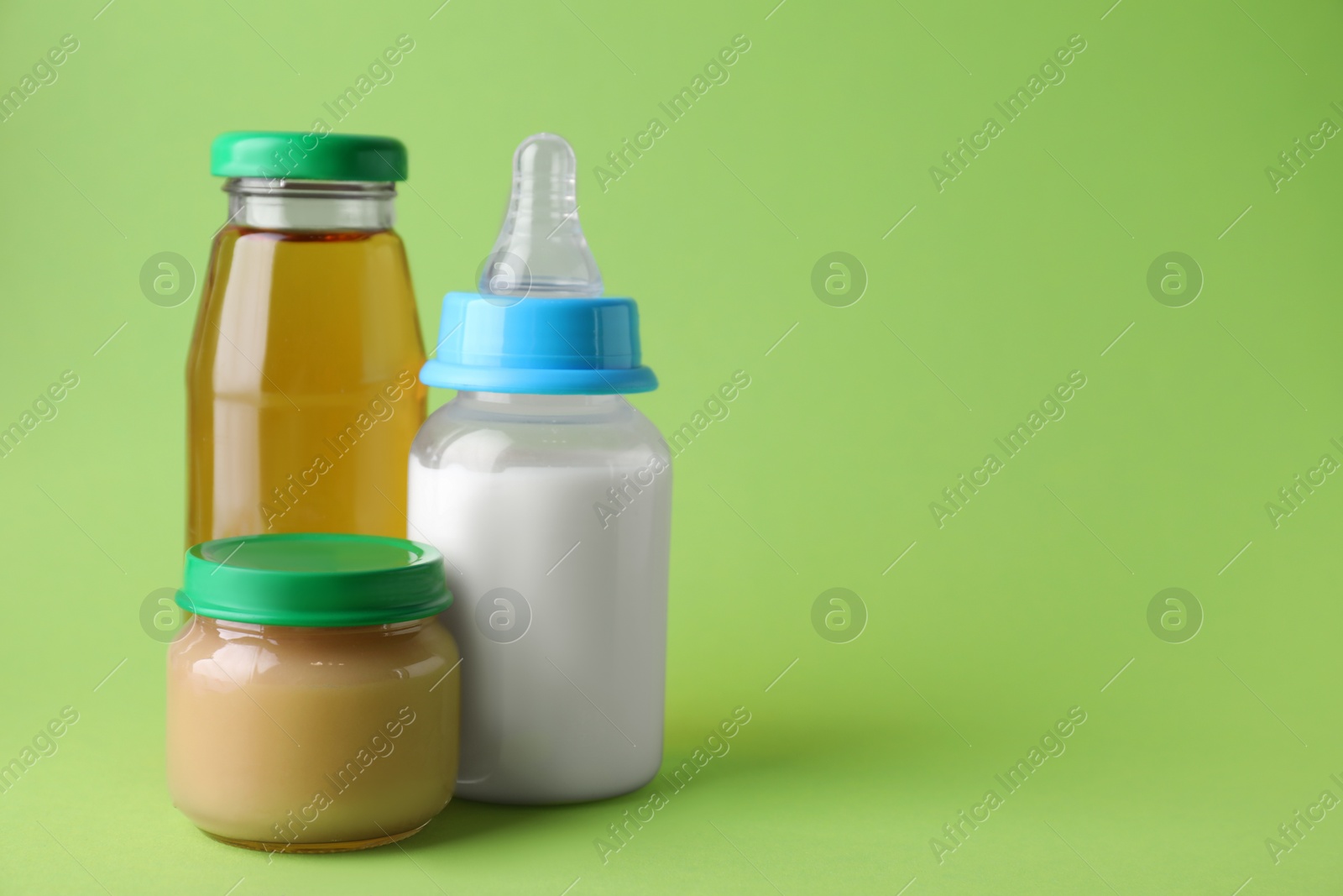 Photo of Healthy baby food, juice and milk on green background, space for text