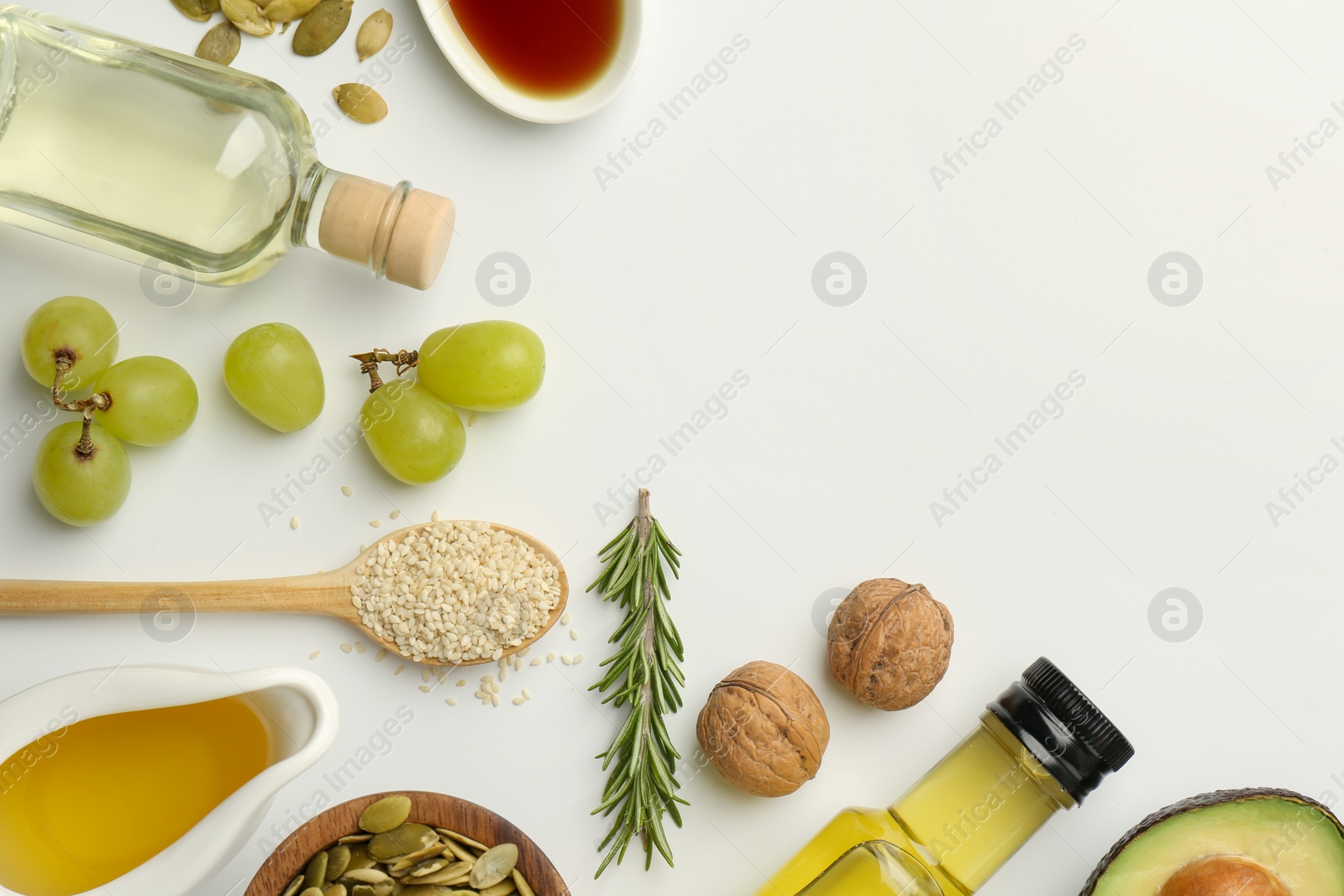 Photo of Vegetable fats. Different oils in glass bottles and ingredients on white table, flat lay. Space for text