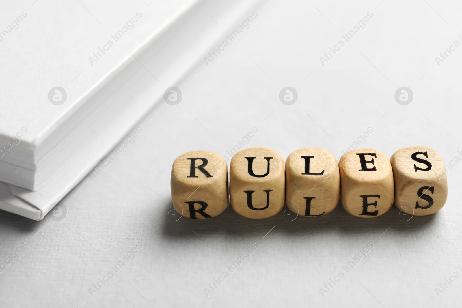 Photo of Word Rules made of wooden cubes with letters and book on white table