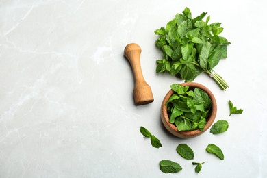 Fresh mint with mortar and pestle on grey marble background, flat lay. Space for text