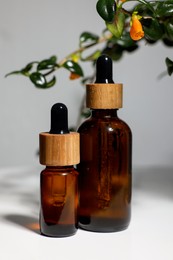 Photo of Glass bottles of essential oil on white table