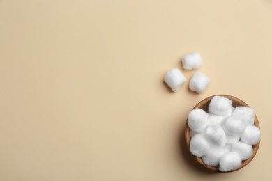 Photo of Bowl with fluffy cotton balls and space for text on color background, flat lay