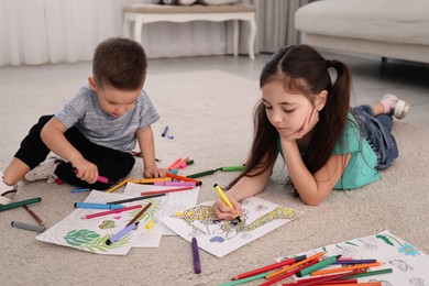Photo of Cute children coloring drawings on floor at home