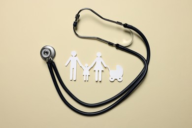 Photo of Paper family figures and stethoscope on beige background, flat lay. Insurance concept