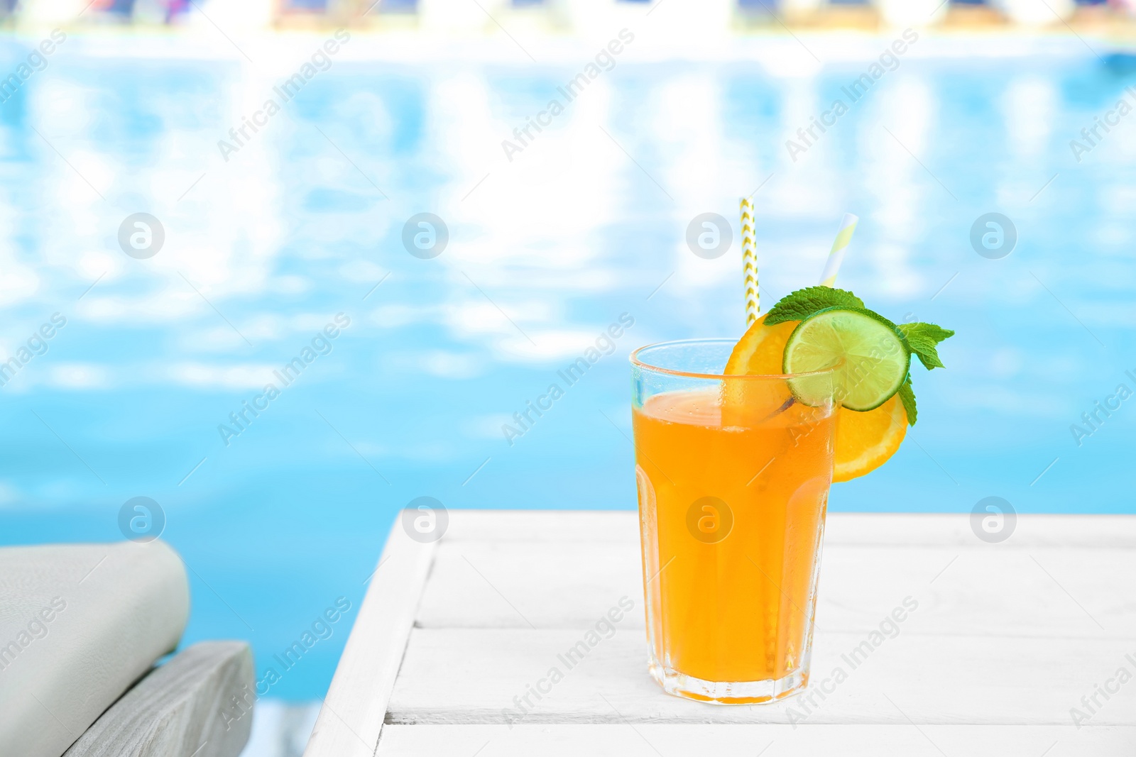 Photo of Refreshing cocktail near outdoor swimming pool on sunny day. Space for text