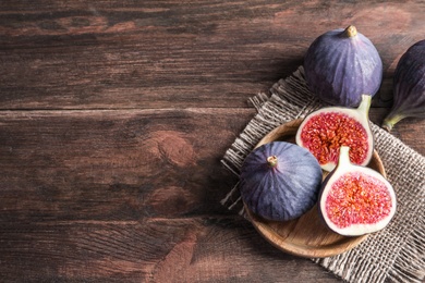 Plate with fresh ripe figs on wooden background, top view. Space for text