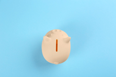 Beige piggy bank on light blue background, top view