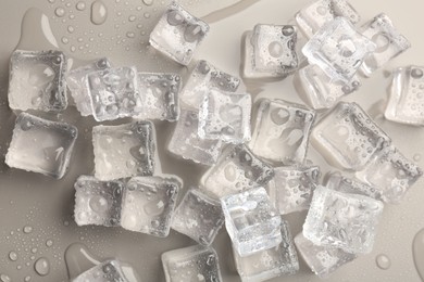 Melting ice cubes and water drops on light grey background, flat lay