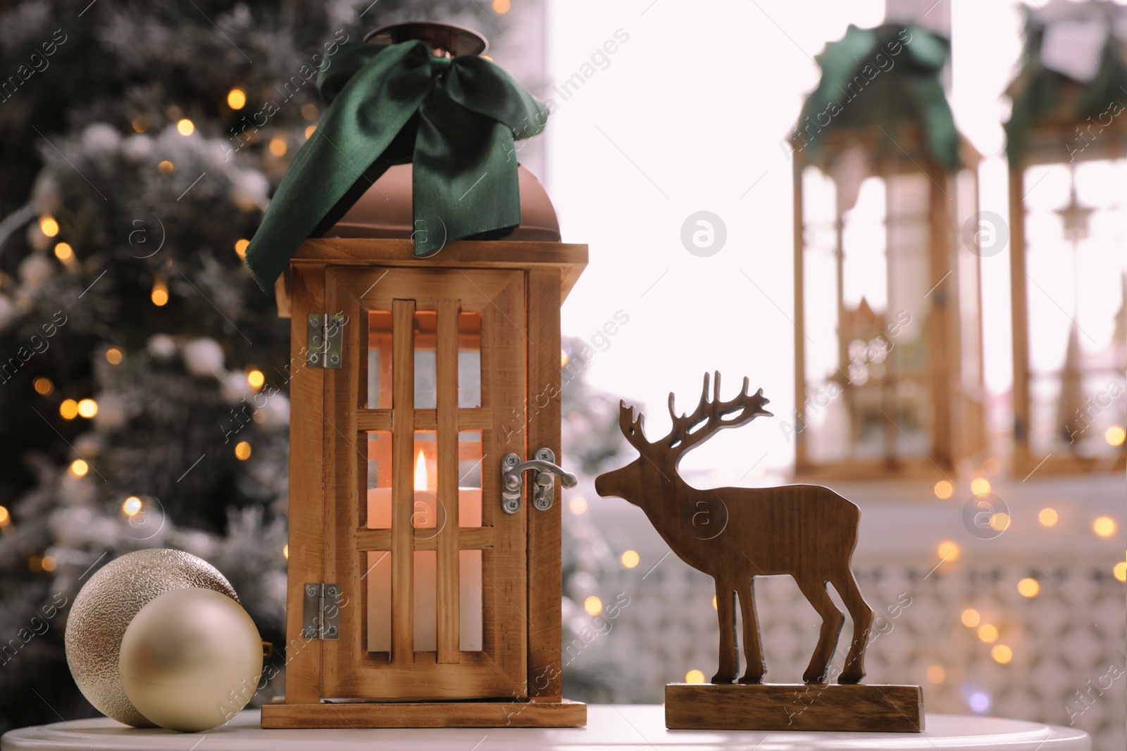 Photo of Beautiful wooden lanterns and other decorations on table in room with Christmas tree