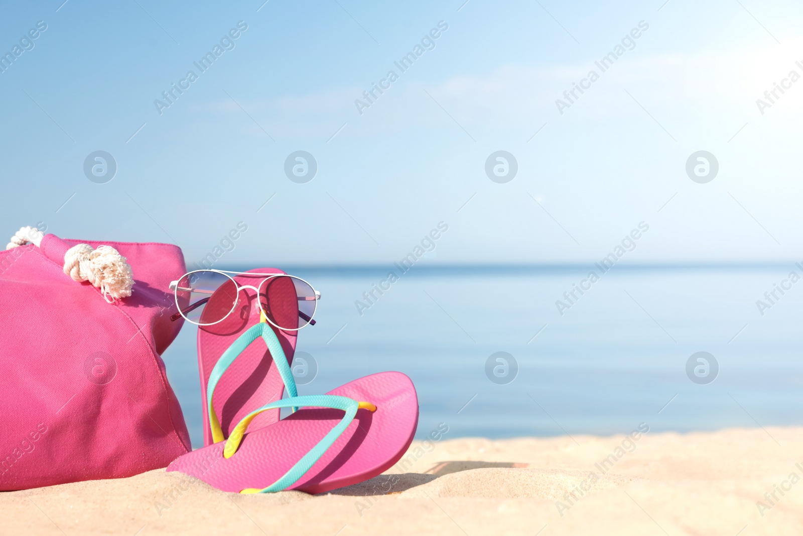 Photo of Stylish beach accessories on sand near sea. Space for text