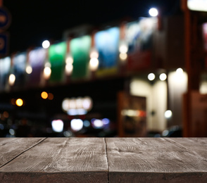 Image of Empty wooden surface and blurred view of night city. Bokeh effect 