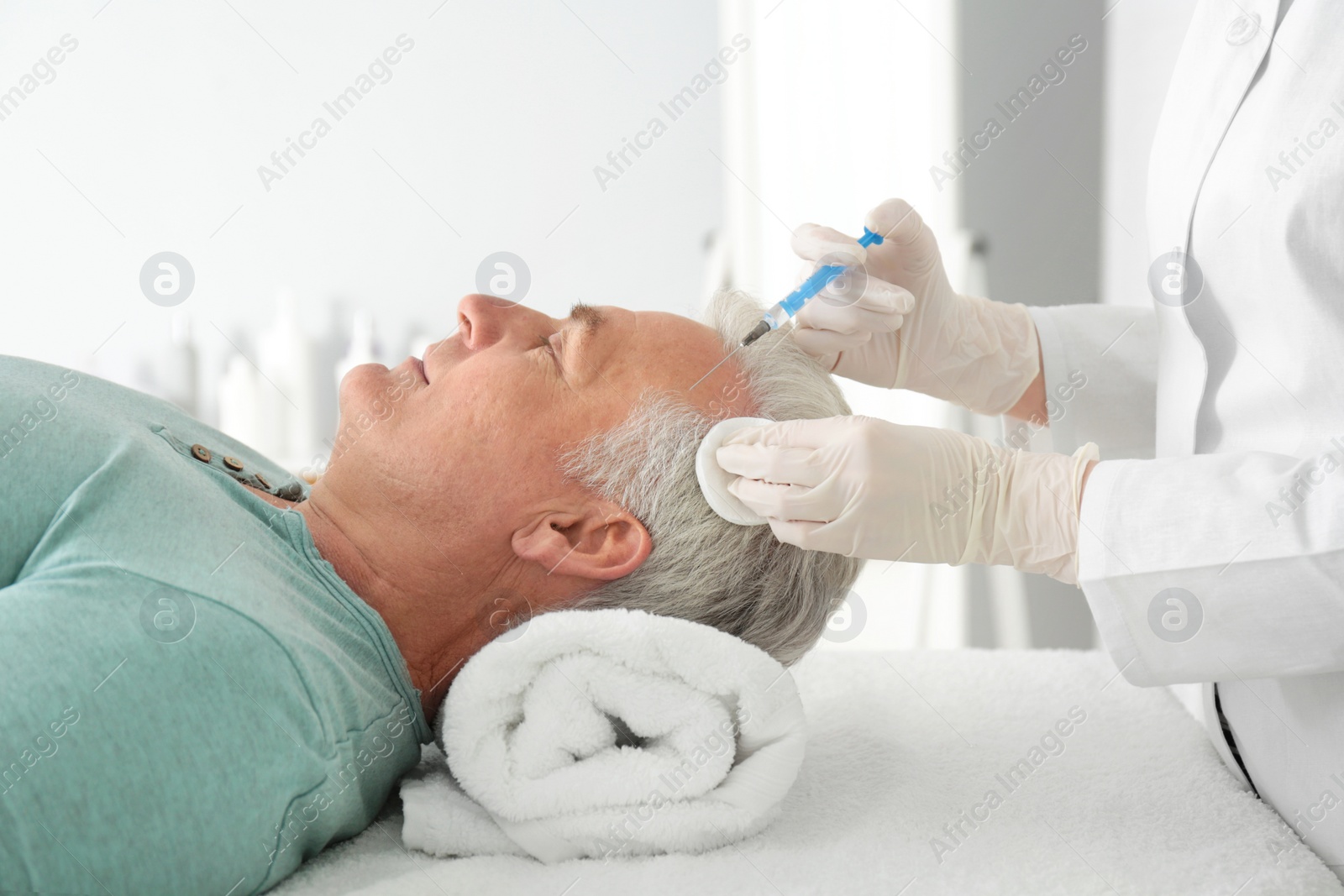 Photo of Senior man with hair loss problem receiving injection in salon