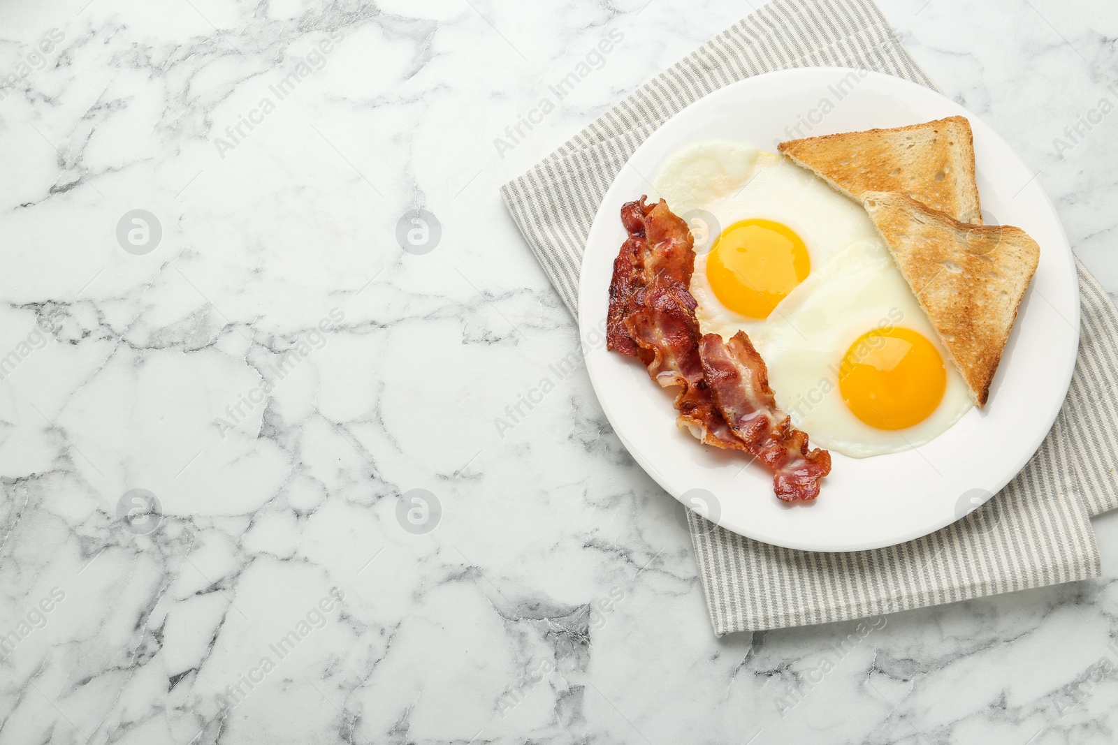 Photo of Delicious breakfast with sunny side up eggs on white marble table, top view. Space for text