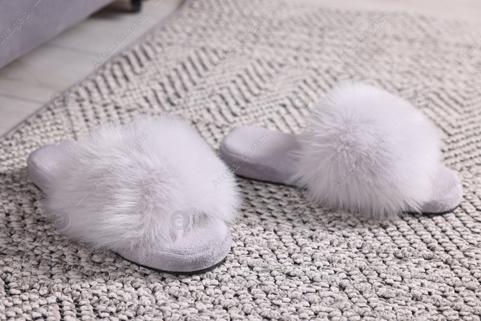 Photo of Grey soft slippers on carpet at home, closeup