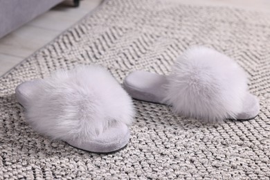 Photo of Grey soft slippers on carpet at home, closeup