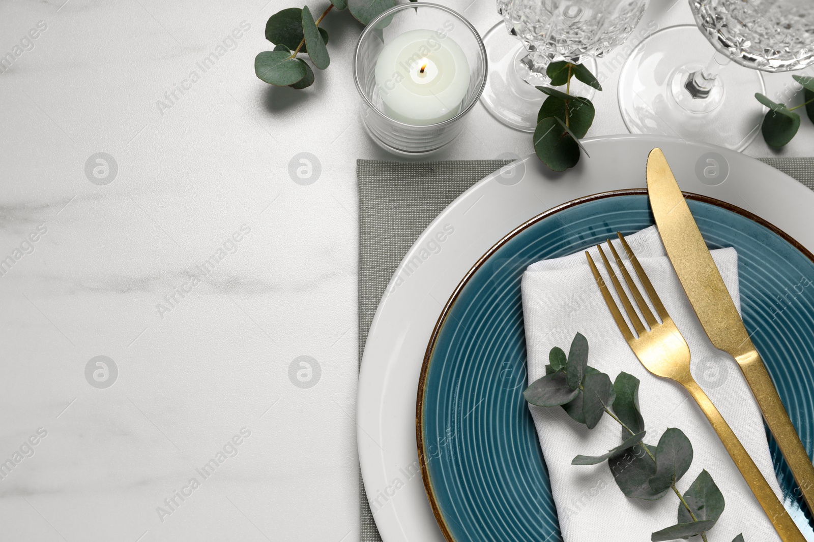 Photo of Stylish setting with cutlery and eucalyptus leaves on white marble table, flat lay. Space for text