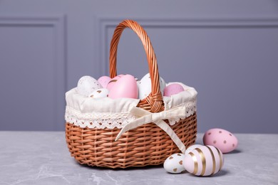 Photo of Easter basket with many painted eggs on grey textured table