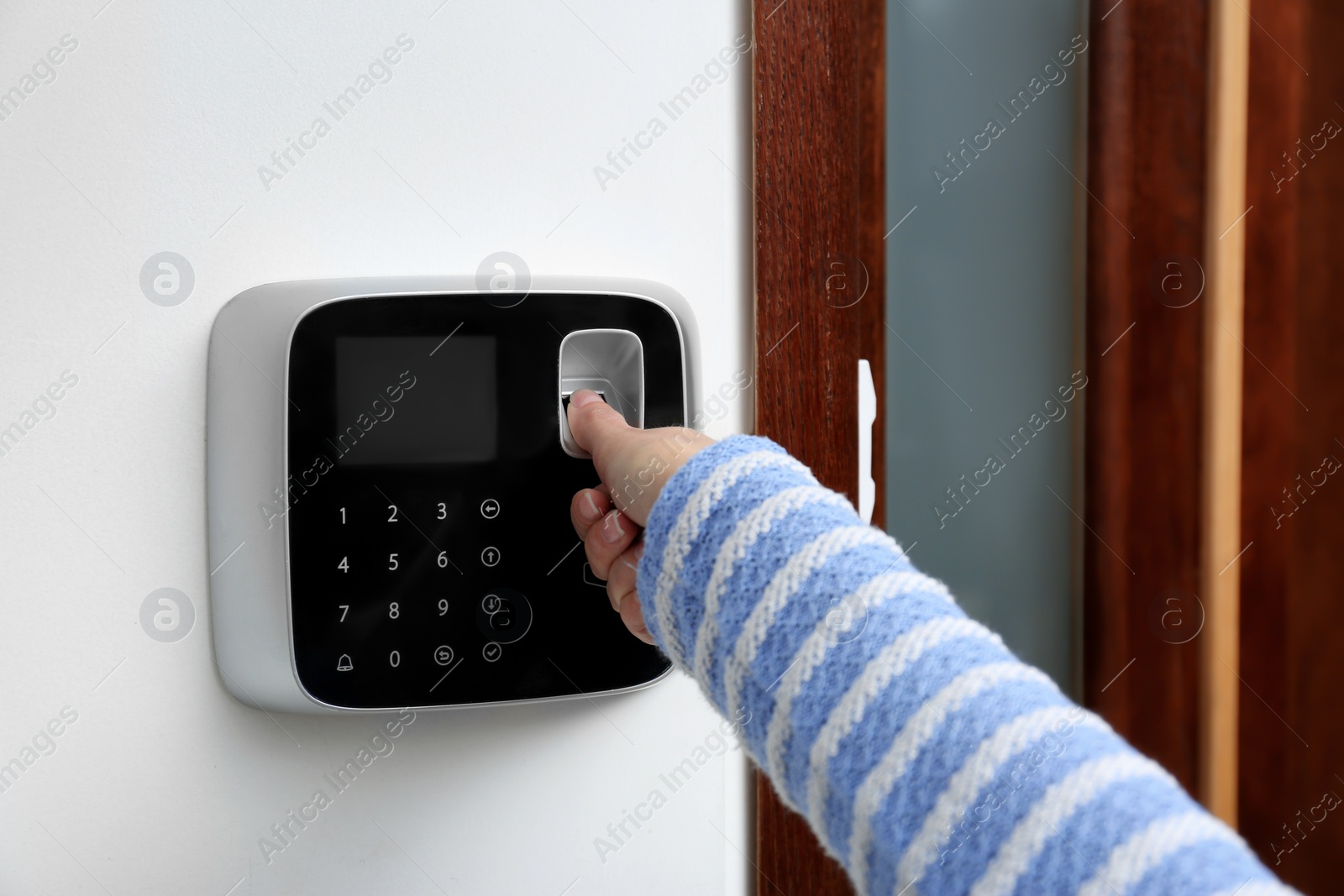 Photo of Woman scanning fingerprint on alarm system indoors, closeup