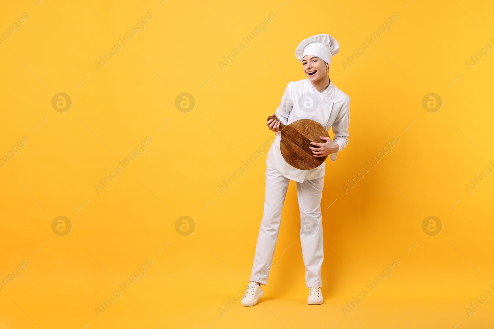 Photo of Professional chef with serving board having fun on yellow background. Space for text