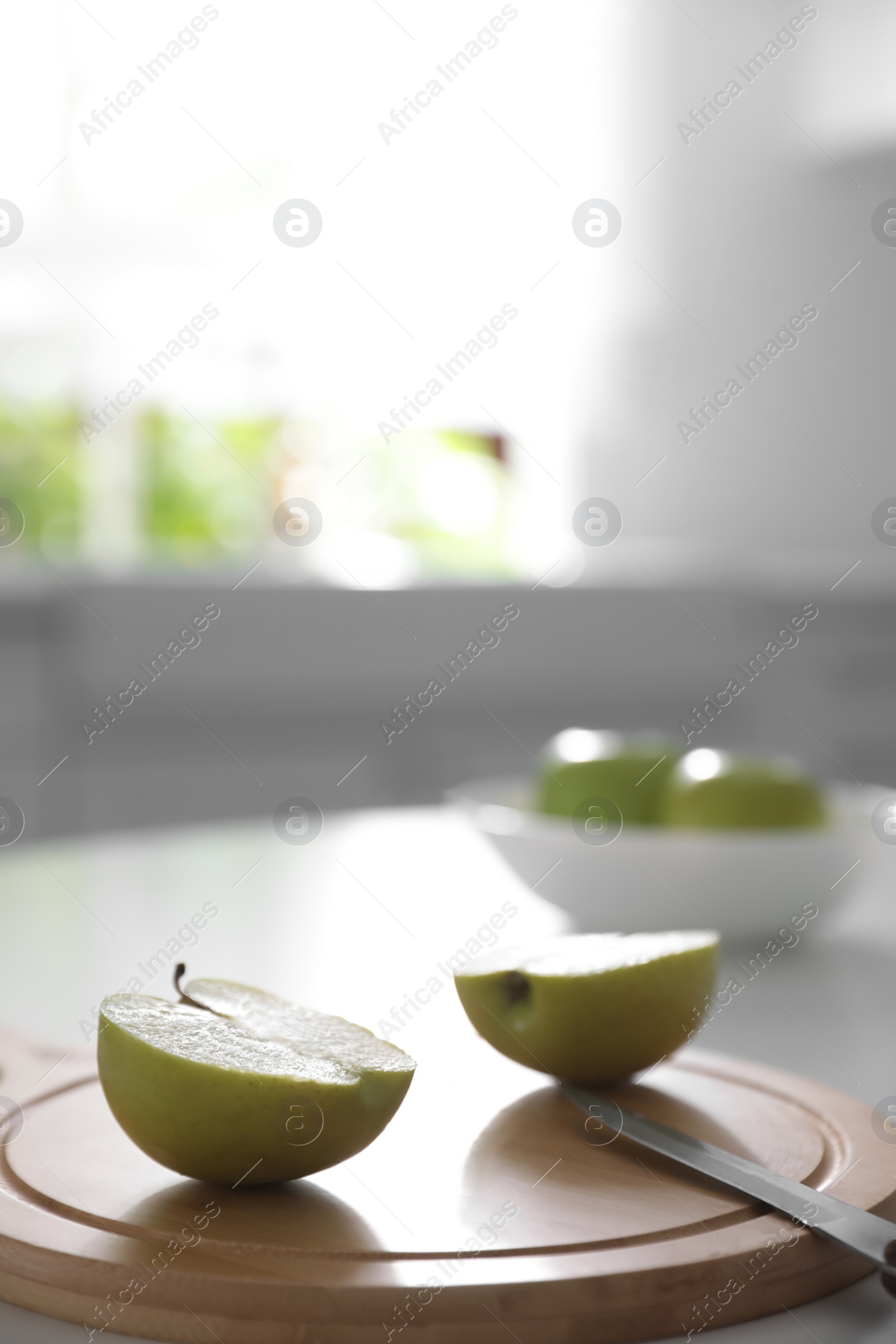 Photo of Halves of fresh apple and knife on white table in kitchen. Space for text