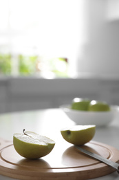 Photo of Halves of fresh apple and knife on white table in kitchen. Space for text