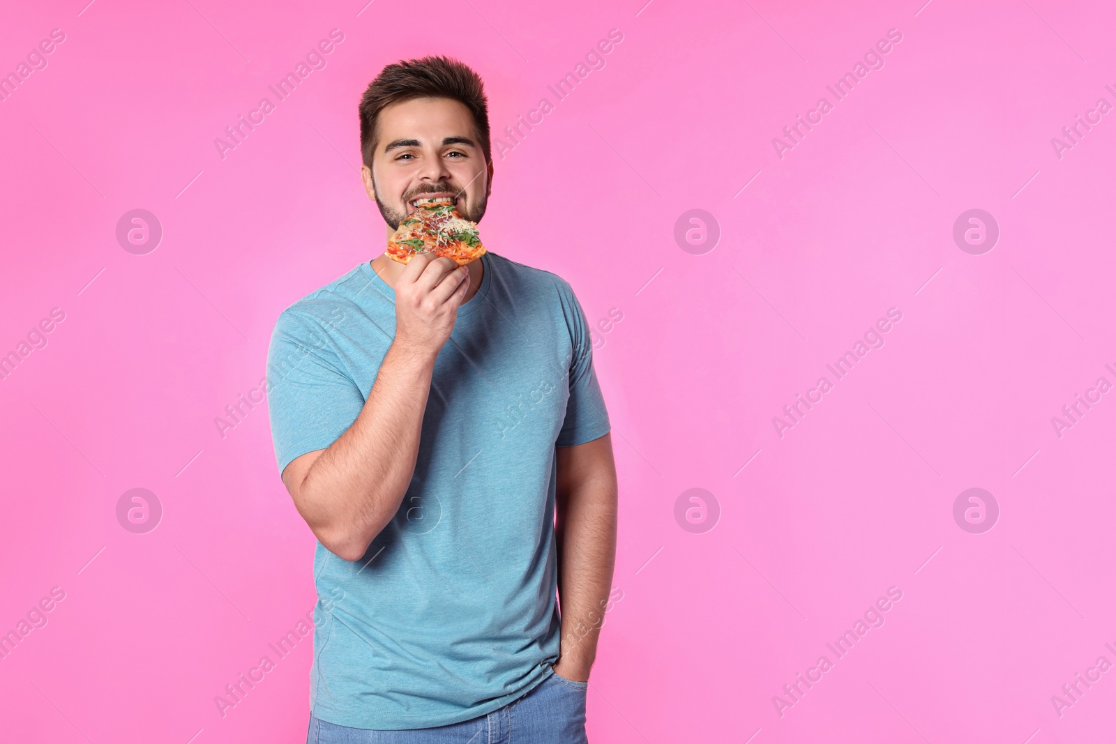 Photo of Handsome man with pizza on pink background, space for text