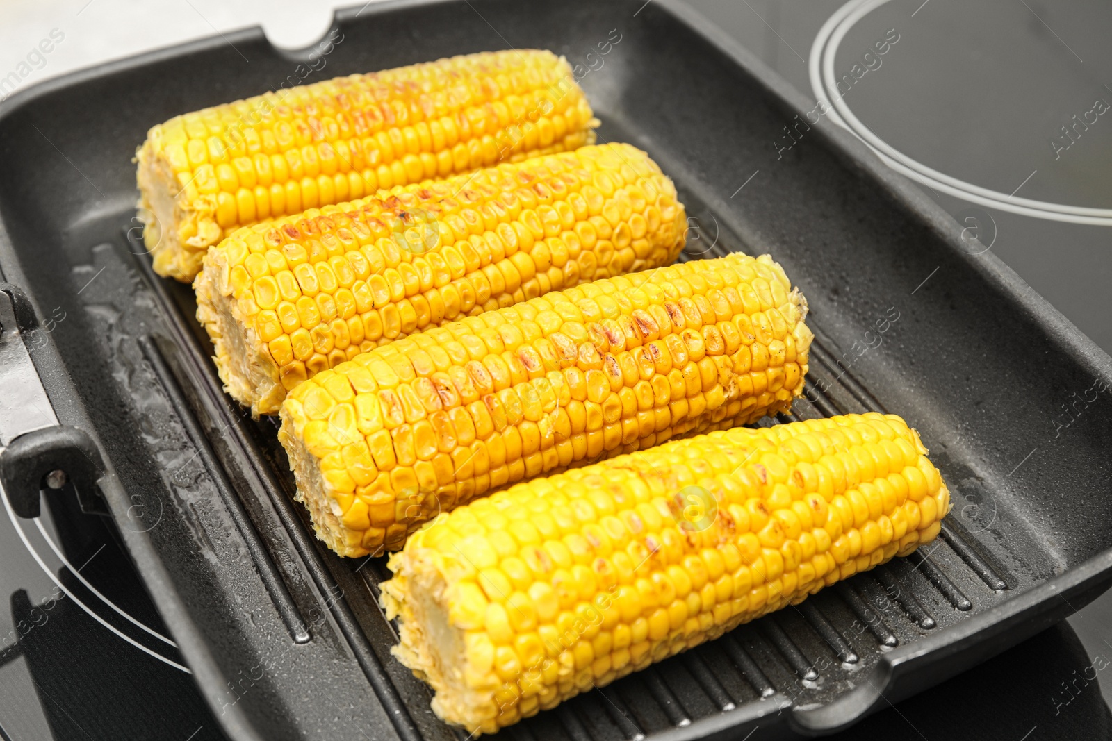 Photo of Fresh corn cobs on grill pan, closeup