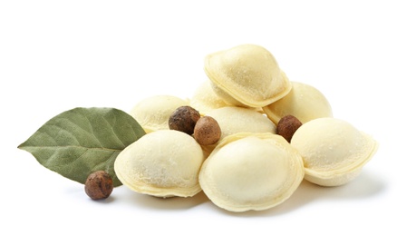 Photo of Pile of raw dumplings with bay leaf and pepper on white background