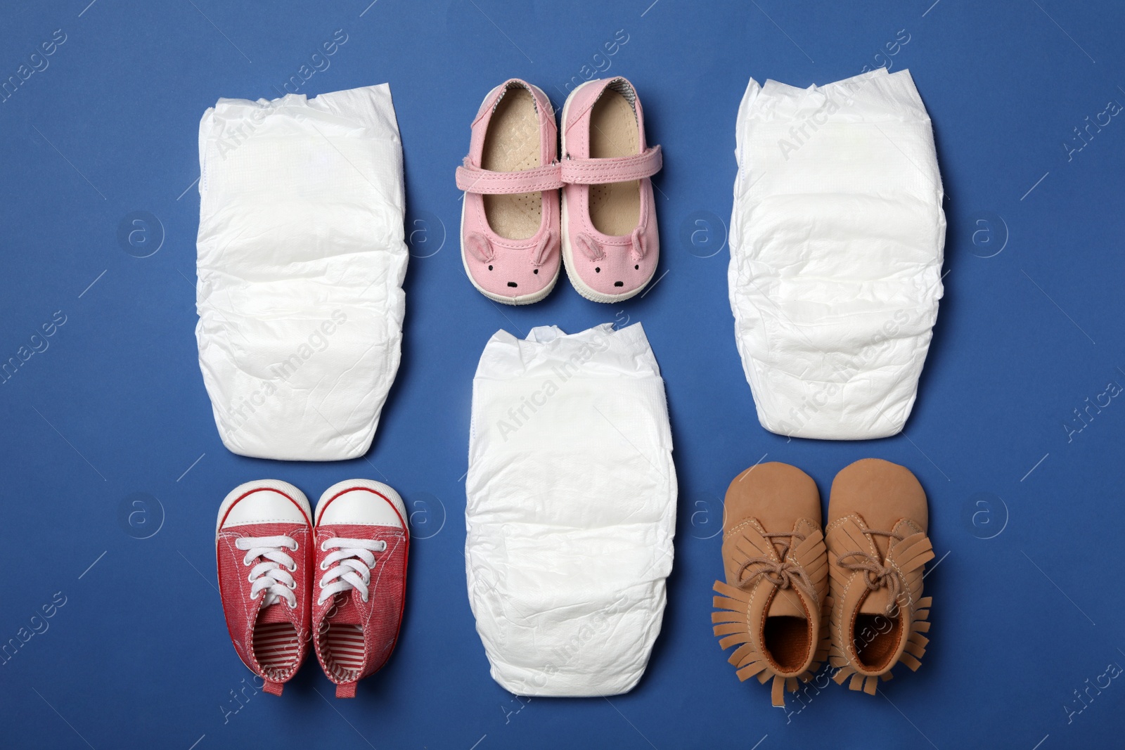 Photo of Diapers and baby accessories on blue background, flat lay