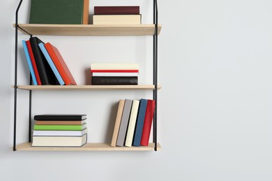 Photo of Shelves with many hardcover books on white wall. Space for text