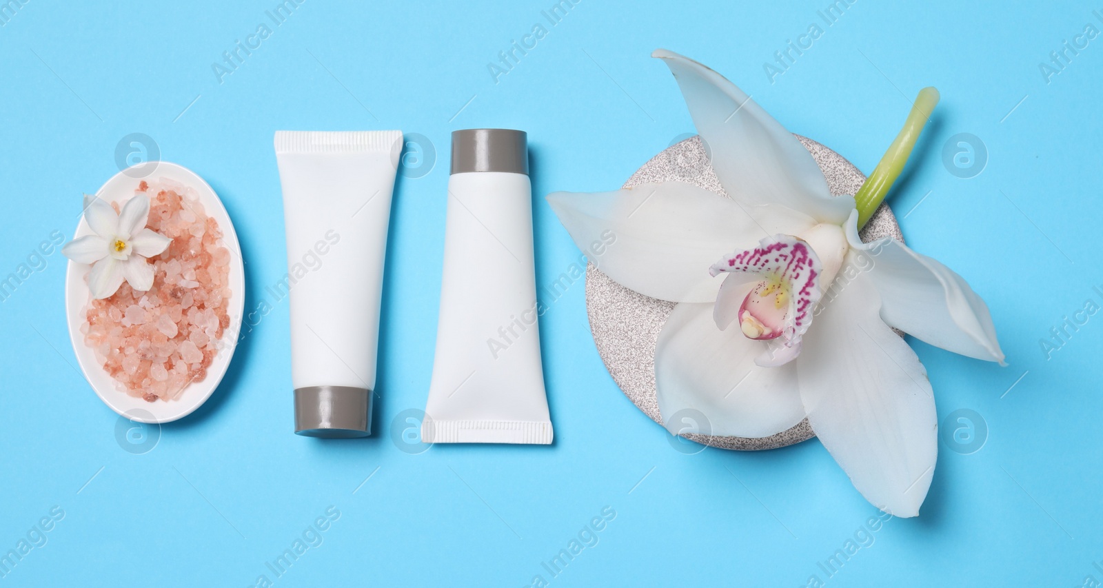 Photo of Flat lay composition with spa products and beautiful flower on light blue background. Space for text