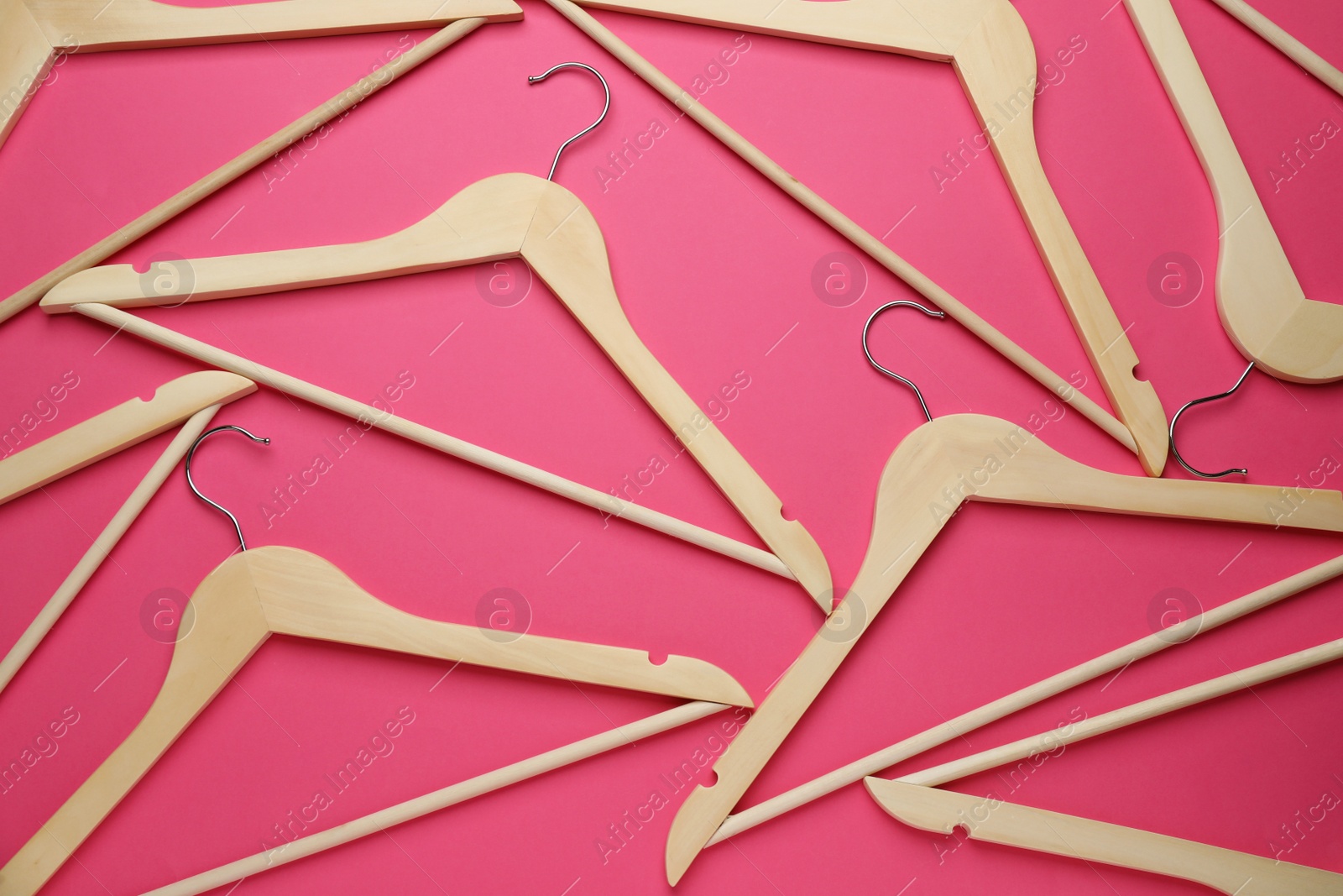 Photo of Empty wooden hangers on pink background, flat lay