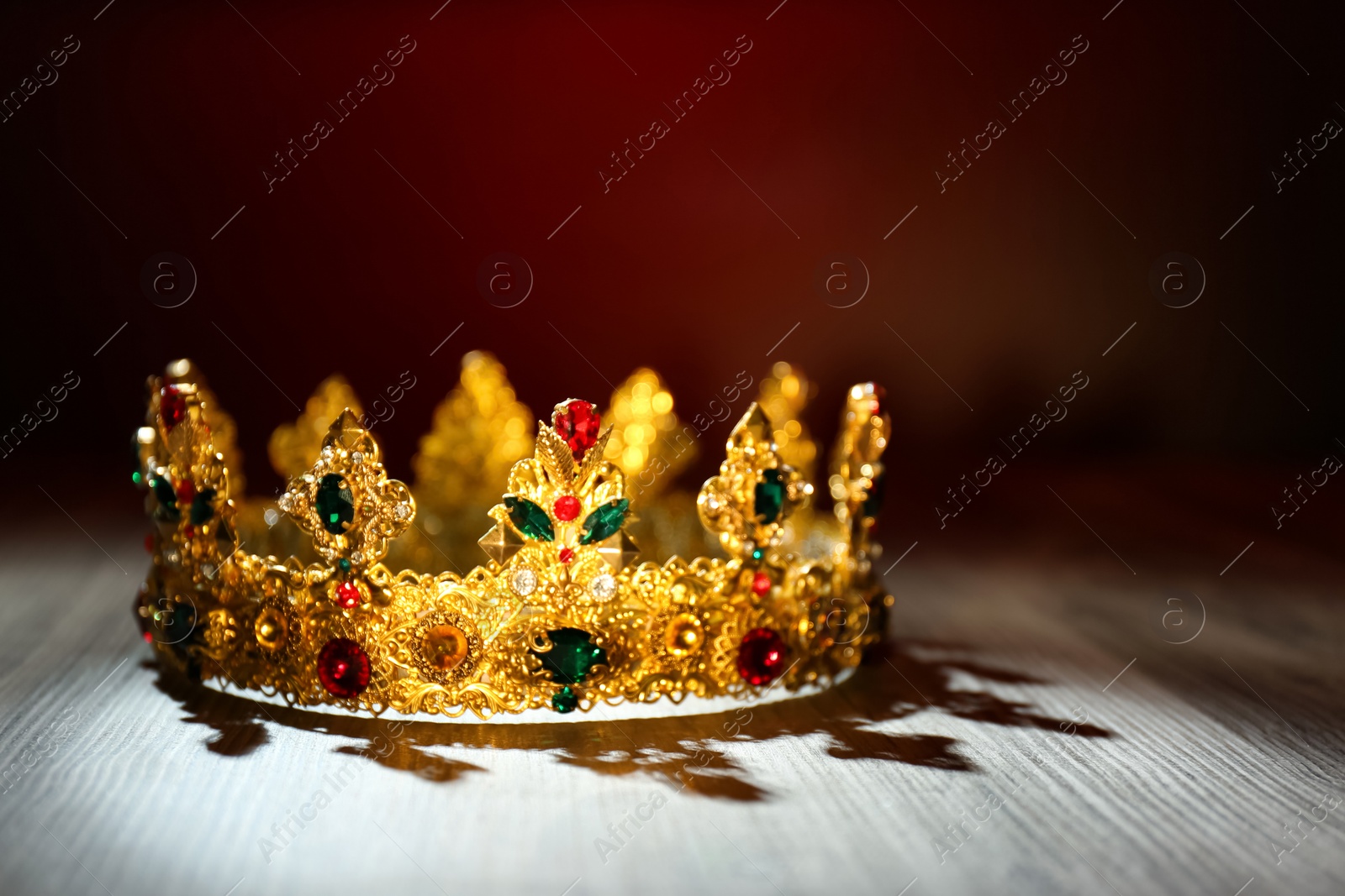 Photo of Beautiful golden crown with gems on wooden table. Fantasy item
