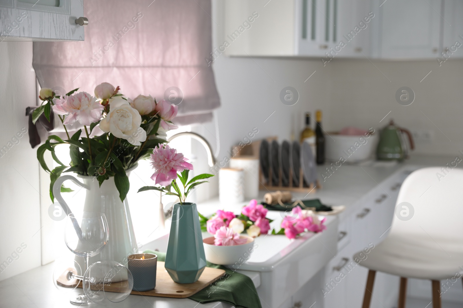 Photo of Beautiful peonies in vases on kitchen counter